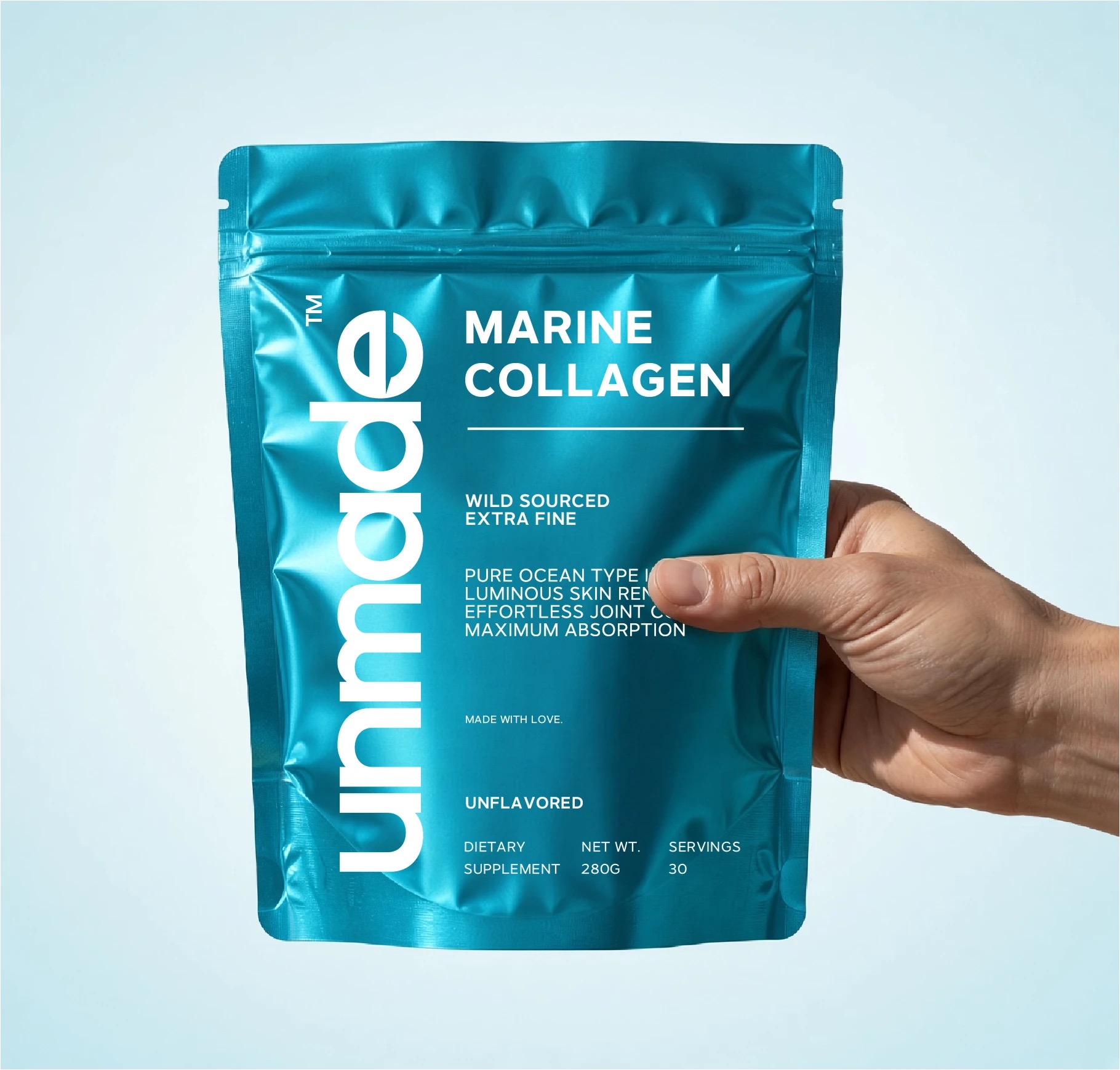 Hand holding an Unmade marine collagen pouch